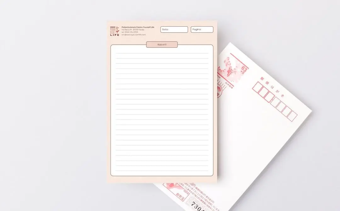 Un blocco appunti bianco con un foglio di carta a righe bianche, accanto ad alcune buste rosa e bianche su uno sfondo bianco